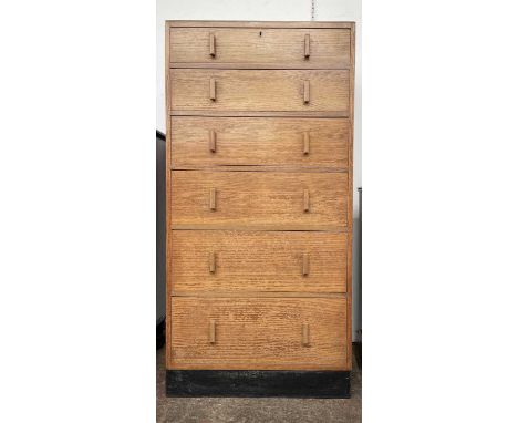 An oak tall chest of six graduated long drawers, 1930s, with raised back and ebonised base, height 142cm, width 68.5cm, depth