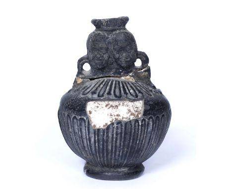 A ROMAN BLACKWARE FLASK of baluster form with fluted body and twin negroid heads (for restoration), 13cm high