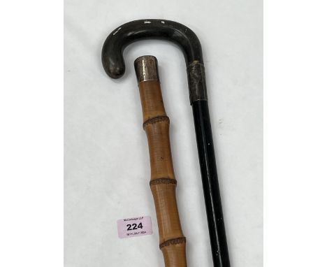 A bamboo walking cane with silver pommel and another stick with silver band.