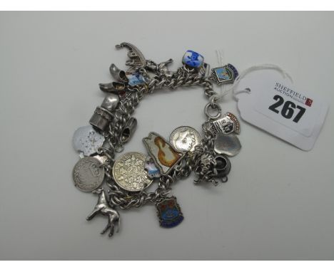 A Curb Link Charm Bracelet, suspending numerous assorted novelty charm pendants, including coins, enamel souvenir shields, we