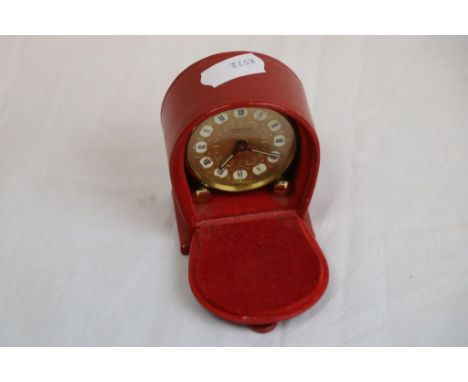 Looping 8 day travel alarm clock, raised on two conical feet, black Roman numerals, rectangular luminous hands, height approx