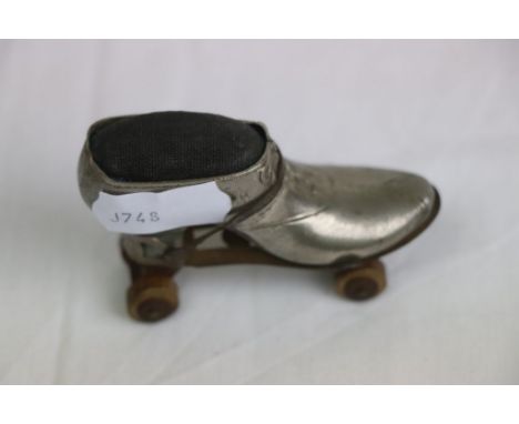 Late Victorian/ Edward white metal pin cushion in the form of a shoe, with roller skate attachment