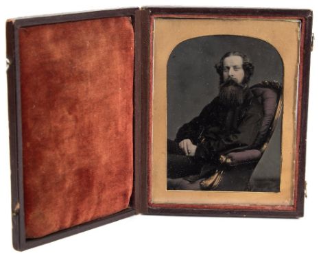 A mid 19th century ambrotype portrait of a bearded gentleman:, photographer unknown, seated  in a carved frame button back ch