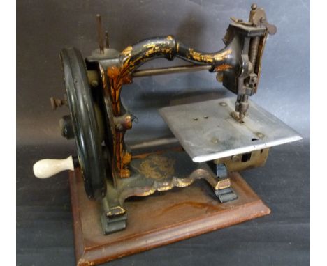 An Early Small Sewing Machine with shaped arm and gilded decoration together with a black slate mantle clock