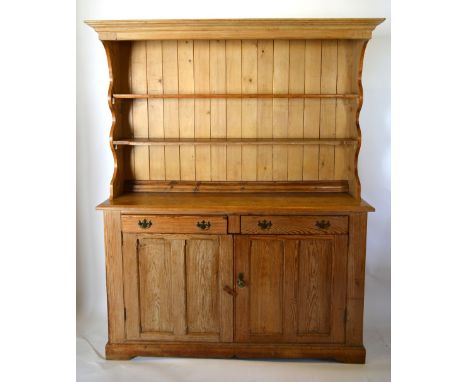 A Late 19th Early 20th Century Pine Dresser, the boarded shelf back above two frieze drawers with brass handles and two cupbo