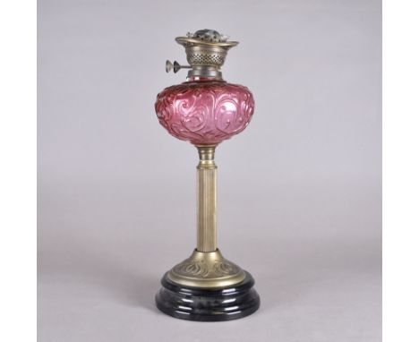 A Victorian cranberry glass oil lamp base, reservoir with scroll decoration, fluted brass stem, black ceramic stepped base, u
