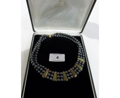 An 18ct hermatite bead and green and gold guilloche enamel three strand necklace by De-Vroomen. 175g gross. Boodle and Duntho