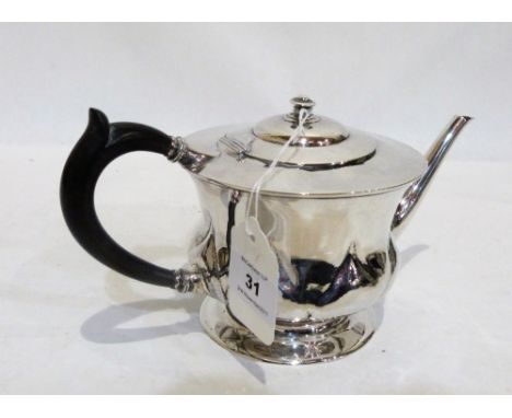 A George V Arts and Crafts silver teapot by W.H Haseler, with hammered lobed body and ebony handle. 5'' high. Birmingham 1911