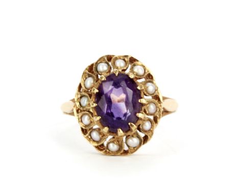 An Edwardian hallmarked 9ct yellow gold ring set with an oval cut amethyst surrounded by seed pearls, (K.5).