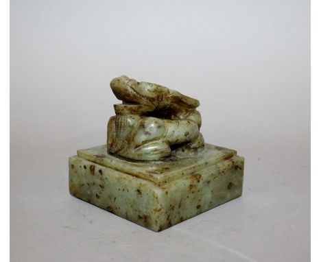 A CHINESE JADE-LIKE SEAL, surmounted by a coiled dragon, the olive-green stone with russet inclusions, 2.9in square & 2.75in 