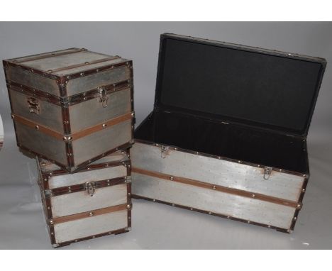 A LARGE ALUMINIUM BOUND TRUNK, 3ft 3ins long, and a pair of matching square trunks, 1ft 4ins.