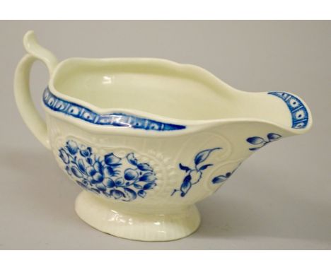 AN 18TH CENTURY WORCESTER SAUCEBOAT of strap flute moulded form decorated with flowers in under-glaze.