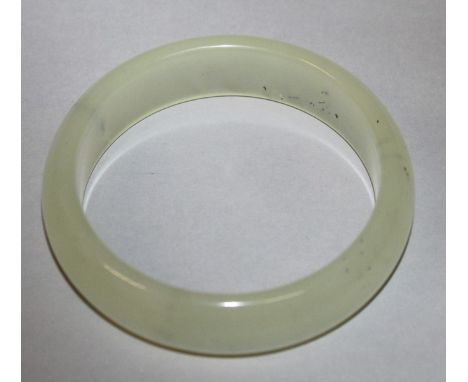A CHINESE CELADON JADE-LIKE BANGLE, of semi-translucent texture, 3in diameter, the inner rim 2.3in diameter.
