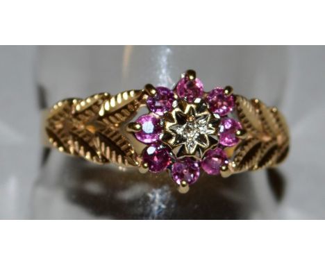 A 9CT GOLD, GARNET AND DIAMOND FLOWER HEAD RING.