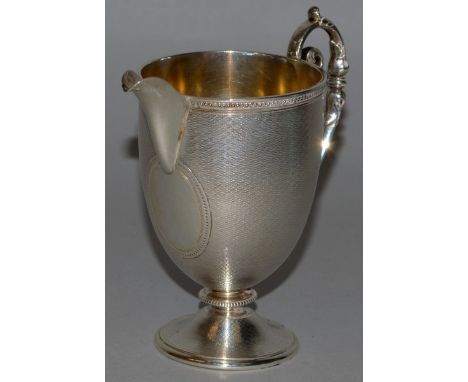 A VICTORIAN ENGINE TURNED CREAM JUG with scrolled handle 5ins high London 1863.
