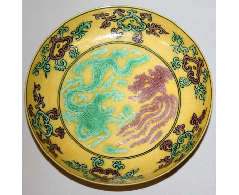 A SMALL CHINESE YELLOW GROUND PORCELAIN DRAGON & PHOENIX DISH, decorated in green and aubergine, each rim with formal ruyi fl