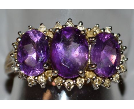 A 9CT GOLD THREE STONE AMETHYST AND DIAMOND RING.