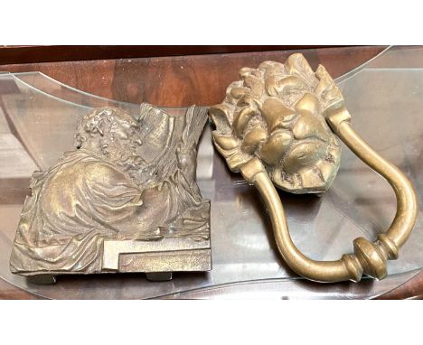 A brass lions head door knocker and a brass depiction of Greek scholar reading 