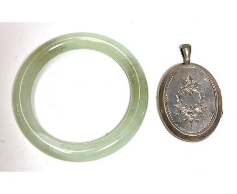 A late 19th century locket with incised decoration to the front and back; a Chinese jade coloured hardstone bangle 