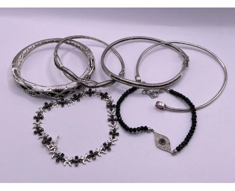 4 silver bangles and 2 bracelets set with black and clear stones, one with 2 red stones 