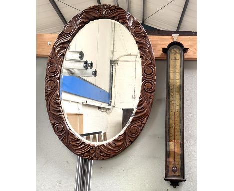 A wall mirror in carved oak oval frame; a pair of raffia seat stools; an aneroid barometer 