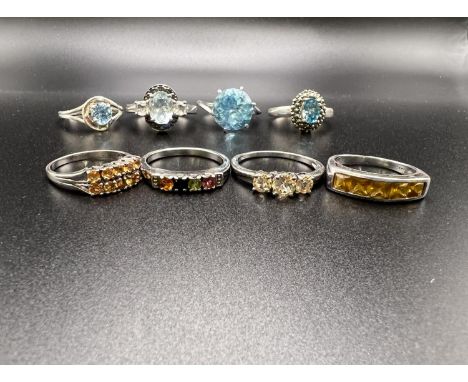 4 silver rings stamped '925' each set with aquamarine coloured stones in a variety of settings; 4 more silver rings set with 