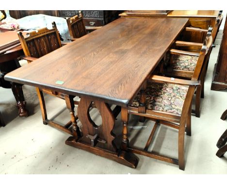 An oak refectory dining table with harp shaped supports, stretcher, with four carver chairs with carved panel backs, length 1