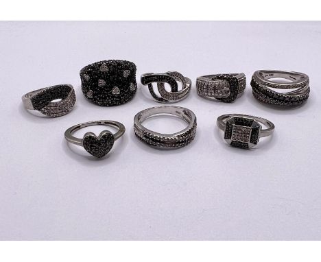 8 silver rings all set with black pave set stone chips, testing as black diamonds, some with similar clear stones, in a varie