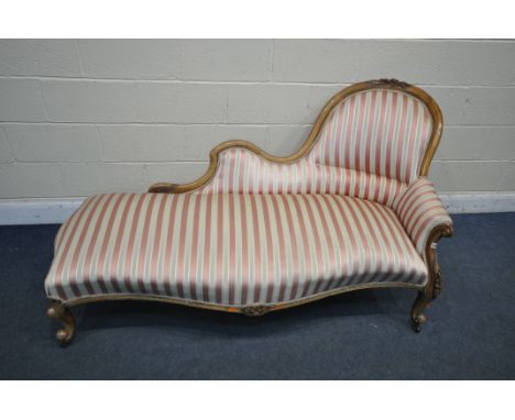 A VICTORIAN WALNUT CHAISE LOUNGE, with a scrolled carved back, later re upholstery, on ceramic castors, width 184cm (conditio