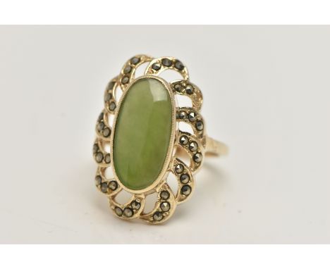 A YELLOW METAL JADE DRESS RING, of a large oval form, set to the centre with an oval cut jade cabochon, in an open work marca