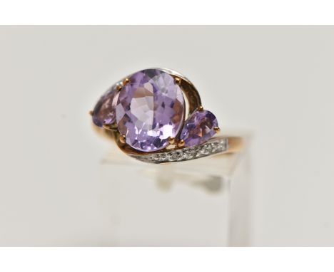 AN AMETHYST AND DIAMOND RING, designed as an oval amethyst flanked by pear shape amethysts to the crossover band set with sin