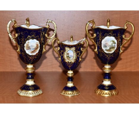THREE EARLY 20TH CENTURY COALPORT THREE HANDLED PEDESTAL VASES, all with blue, pale yellow and gilt ground, all hand painted 