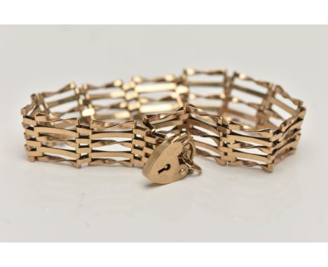 A 9CT GOLD GATE BRACELET, a yellow gold five bar gate bracelet fitted with a heart padlock clasp and safety chain, hallmarked