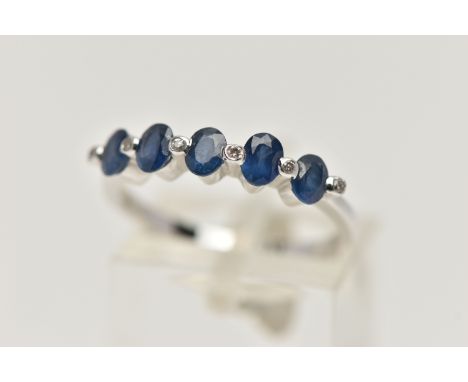 A WHITE METAL SAPPHIRE AND DIAMOND HALF ETERNITY RING, designed with a row of five oval cut blue sapphires, tension set betwe