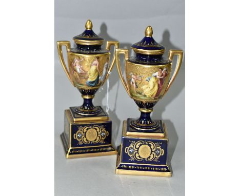 A PAIR OF VIENNA STYLE PORCELAIN TWIN HANDLED PEDESTAL  VASES WITH COVERS, cobalt blue and gilt ground with enamel detail, pa