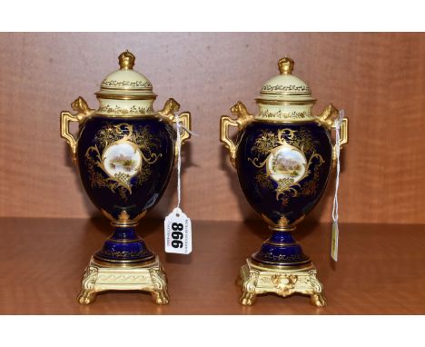 A PAIR OF EARLY 20TH CENTURY COALPORT COVERED PEDESTAL VASES ON INTEGRAL BASES, blue, pale yellow and gilt ground, the domed 