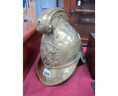 A Fire Brigade Helmet in Brass, circa 1900 with cross axes and torch to front, chin strap absent, 24cm high.