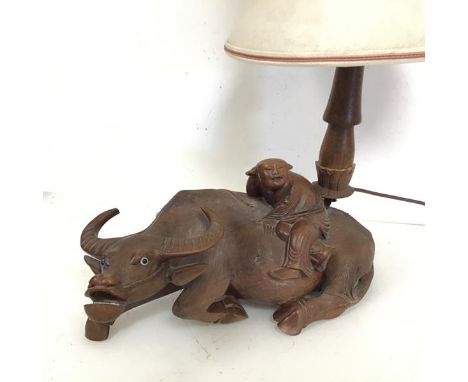 A Chinese carved hardwood table lamp in the form of an Ox with Rider (to top of lampholder: 34cm x 39cm x 16cm)