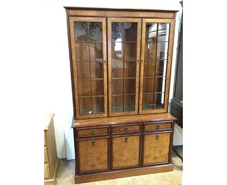 A modern mahogany bookcase, fitted three glazed doors and glass shelves, on base fitted three drawers above two cabinets, on 