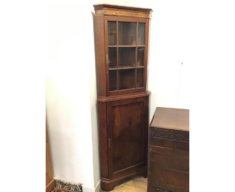 An early 19thc corner cabinet with walnut veneered frieze to cornice, the upper section with glazed door above a lower sectio