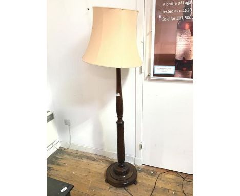 A mahogany standard lamp with turned body and leaf carving to base, on dished circular base (with shade: 178cm)