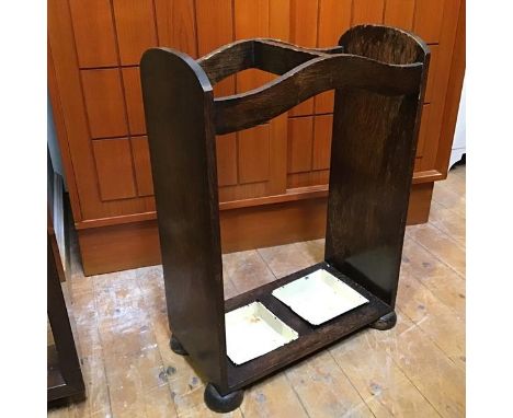 A 1920s oak stick stand, with central divider and two drip trays on bun feet (83cm x 45cm x 24cm)