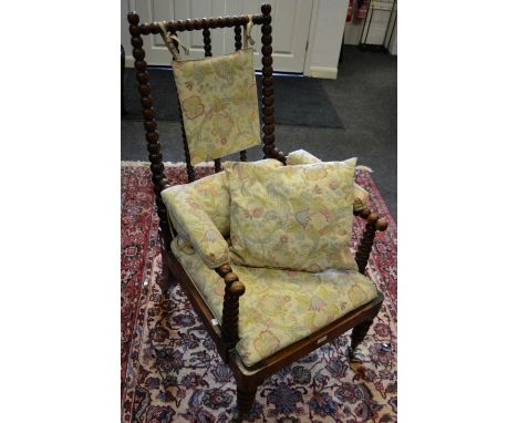 A Victorian rosewood open arm chair bobbin turned uprights and spindles, padded arms, bobbin turned fore legs, brass casters