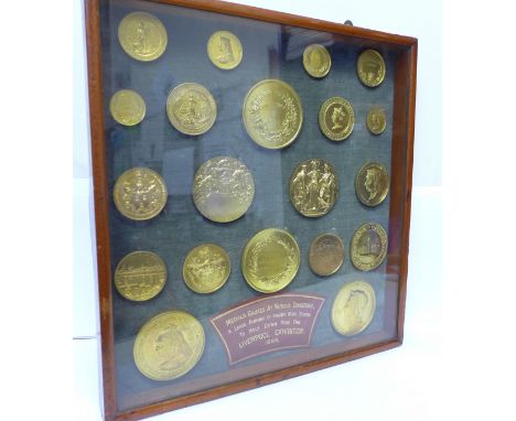 A collection of Walker &amp; Hall medallions from various exhibitions 1886 in a framed display case