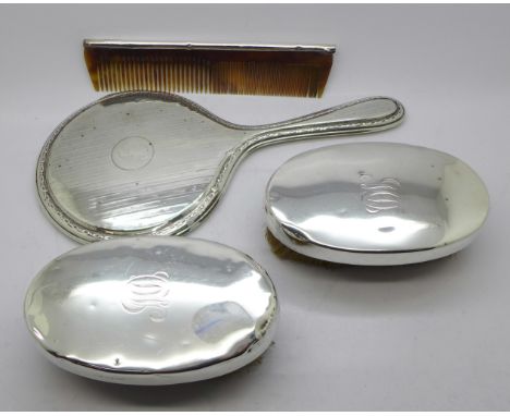 A silver backed mirror, two brushes and a comb