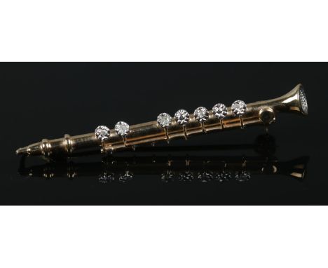 A 9ct Gold clarinet brooch, set with diamonds within an illusion setting to the keys. Length: 4.5cm. Total weight: 2.3g.