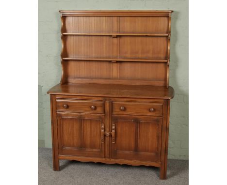 A vintage Ercol elm two part sideboard dresser with shelf, the base has two drawers and two twin-panel cupboards, bears a Erc