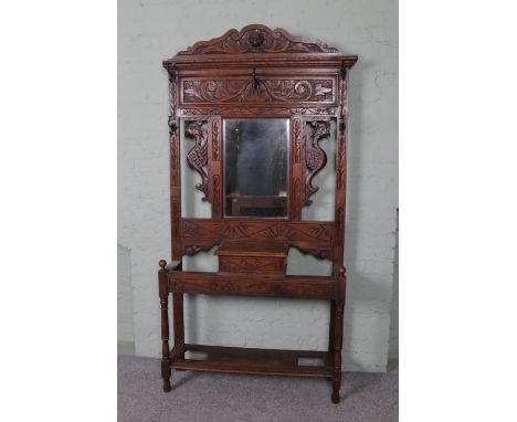 An extensively carved oak hall stand. Featuring central bevel edged mirror and storage box situated between a pair of stylise
