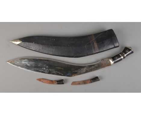 A large Indian Kukri knife with lion mask pommel housed in sheath with two small knives.