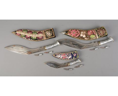 Three Indian Kukri knives each housed in heavily beaded sheaths with two smaller knives.